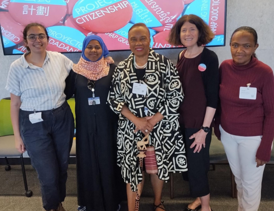 A group of people standing in front of a projection of Project Citizenship's logo